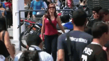 a woman in a red tank top is walking through a crowd