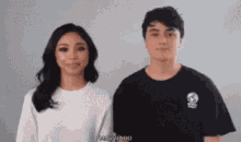 a man and a woman are standing next to each other and the man is wearing a black shirt with a skull on it