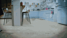 a kitchen with blue cabinets and a white refrigerator is being filmed