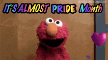 elmo from sesame street is holding a purple heart and saying it 's almost pride month .