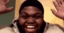 a close up of a person 's face with their hands up .
