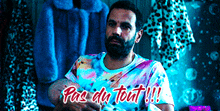 a man in a tie dye shirt is holding a video game controller and says " pas du tout "