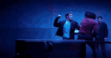 two men are fighting in a dark room in front of a red wall .