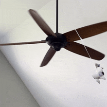 a ceiling fan with wooden blades is spinning on a white ceiling