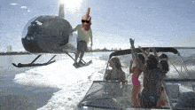 a group of people on a boat with a man in a helicopter giving a middle finger