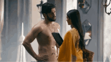a shirtless man and a woman are standing next to each other .