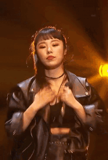 a woman wearing a leather jacket and a choker is standing on a stage .