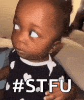 a baby girl is making a funny face and says stfu .