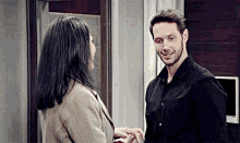 a man and a woman are standing next to each other holding hands and smiling .