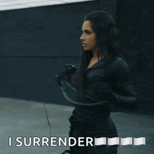 a woman in a black suit is holding a whip and the words i surrender are above her