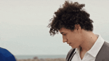 a young man with curly hair is looking down