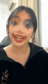 a woman with a clown makeup on her face is making a funny face .
