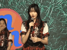 a girl is holding a microphone in front of a sign that says " n "