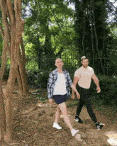 two men walking in the woods with one wearing a t-shirt that says adidas