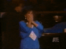 a woman in a blue dress giving a thumbs up sign
