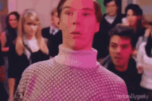 a man in a sweater is standing in front of a crowd of people .