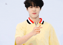 a young man in a yellow shirt is making a heart shape with his hands