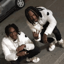 two men in white jackets are squatting on the ground