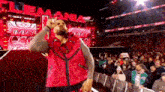 a man in a red vest is standing in front of a crowd .