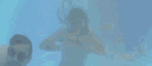 a man and woman are swimming underwater in a swimming pool .
