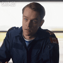 a man in a blue uniform has a canadian flag patch on his sleeve