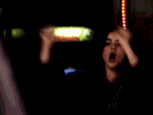 a woman is screaming in a dark room with her mouth open