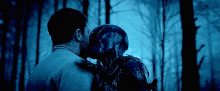 a man is kissing a monster in a dark forest .