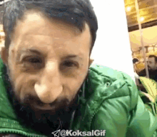 a man with a beard is wearing a green jacket with the hashtag @koksalgif