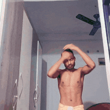 a shirtless man is standing in a room with a ceiling fan