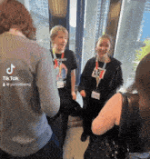 a group of people standing in front of a window with tiktok written on the back of one of them
