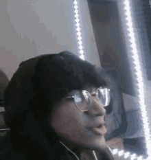 a man wearing glasses and headphones is sitting in front of a window .