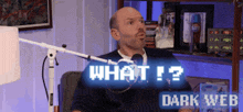 a man sitting in front of a microphone with the words what ! ? dark web