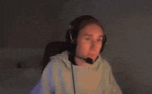 a woman is wearing headphones and a microphone while sitting in front of a computer screen .