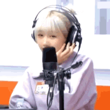 a girl is wearing headphones and talking into a microphone .