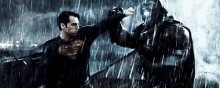 superman and batman are fighting in the rain in a movie .