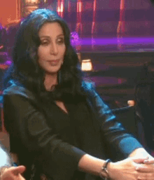 a woman is sitting at a table with her hands folded in front of her .