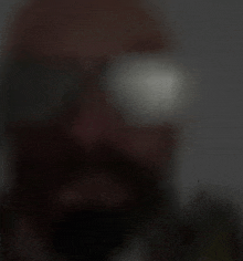 a blurry picture of a man with a beard wearing glasses