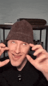 a man wearing a brown hat is making a face with his hands