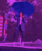 a woman holding a blue umbrella stands in front of a sign that says early
