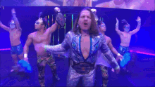 a group of wrestlers are standing on a stage and one of them is wearing a championship belt