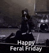 a black and white photo of a person standing on a stage with the words `` happy feral friday '' written on it .