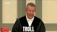 a man in a judge 's robe is talking into a microphone and says troll .