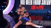a wrestler is holding another wrestler in a blue shirt with the words one week from saturd live on ppu