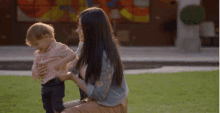 a woman and a child are playing in a grassy area