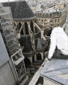a man sits on the edge of a building looking down at the city