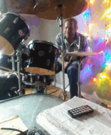 a man playing drums in front of a christmas tree and a remote control
