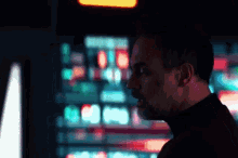 a man in a black turtleneck is standing in front of a computer monitor