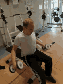 a man in a white shirt is lifting a dumbbell in a gym