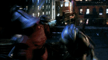 two ninja turtles are fighting each other in front of a building