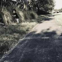 a little boy is standing on a sidewalk near a grassy area